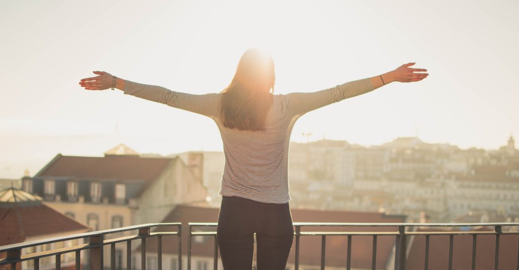 sun shining on woman with her arms stretched out