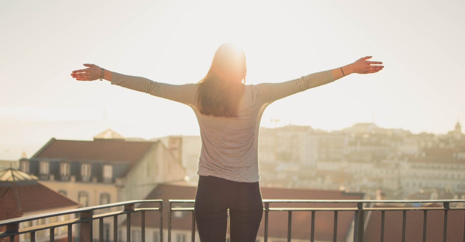 sun shining on woman with her arms stretched out