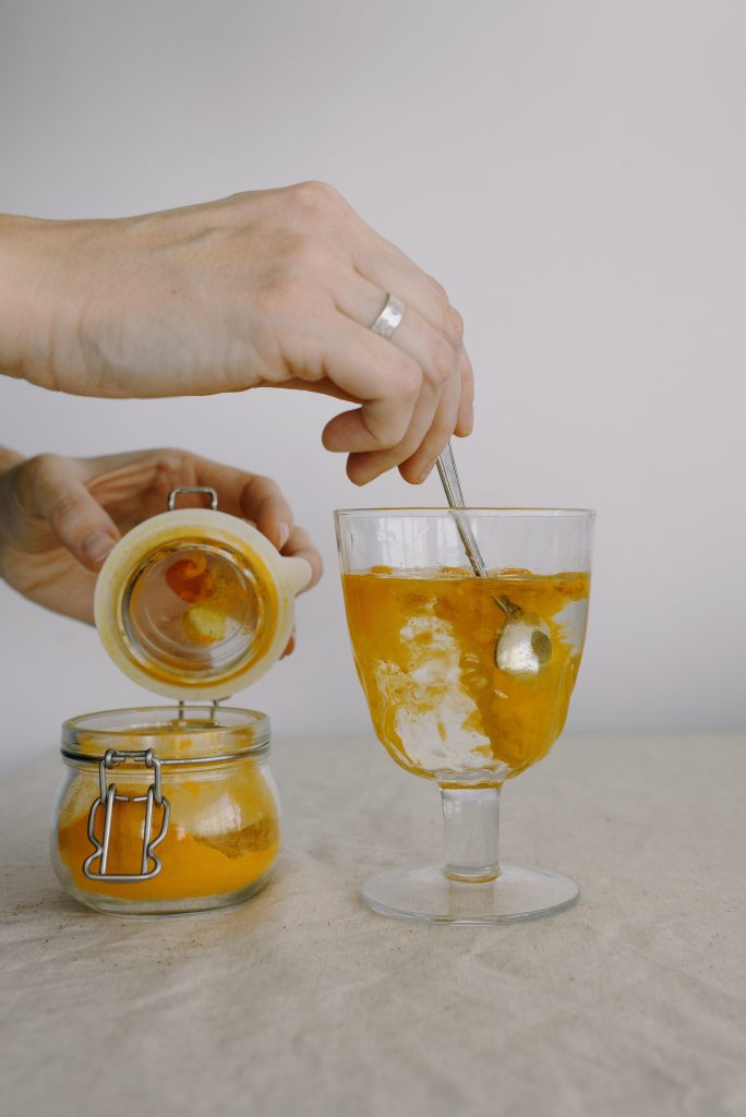 turmeric being stirred in a glass of water